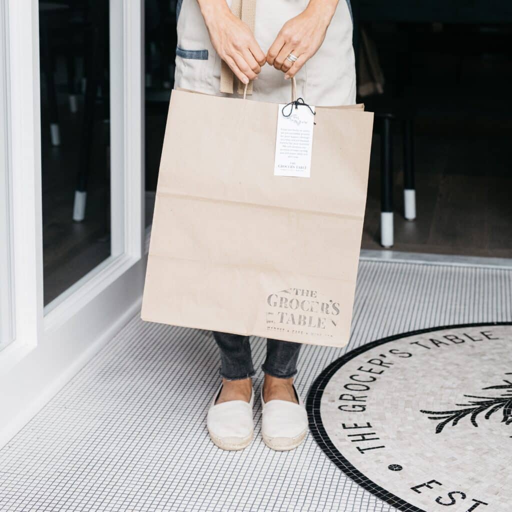 Woman holding The Grocer's Table to-go bag